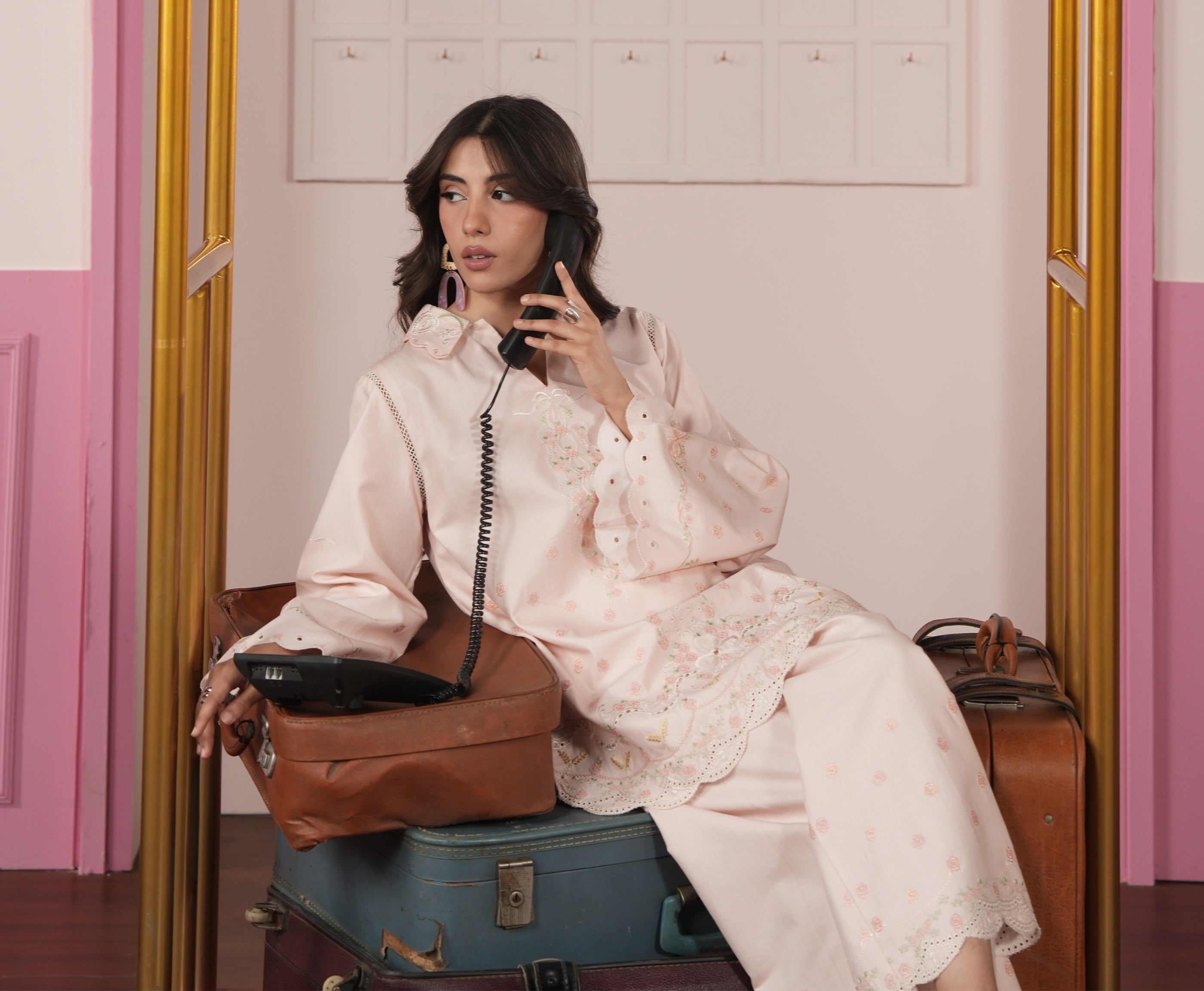 Woman sitting on a suitcase with a vintage phone, surrounded by suitcases and bags.