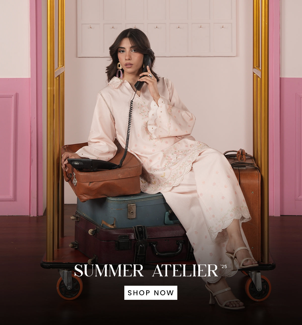 Woman in a white outfit sitting on a suitcase with 'Summer Atelier' branding.