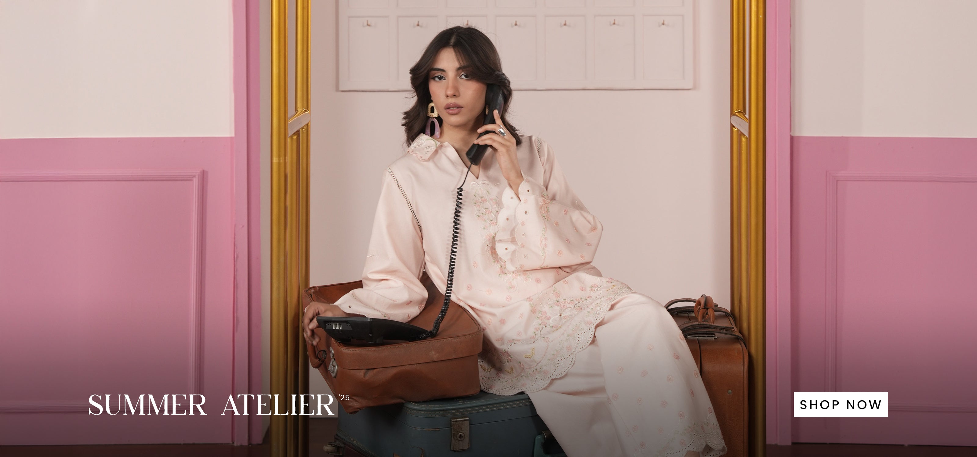 Woman in a vintage setting with pink walls and a suitcase, holding a phone. 'Summer Atelier' brand visible.